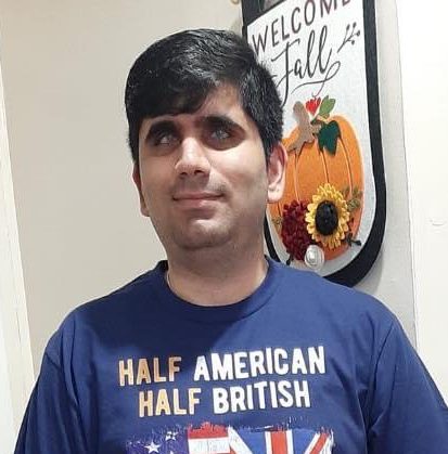 Picture of Khushal Dodia wearing a blue shirt with the American and United Kingdom flag with text that reads Half American, Half British, 100% Awesome